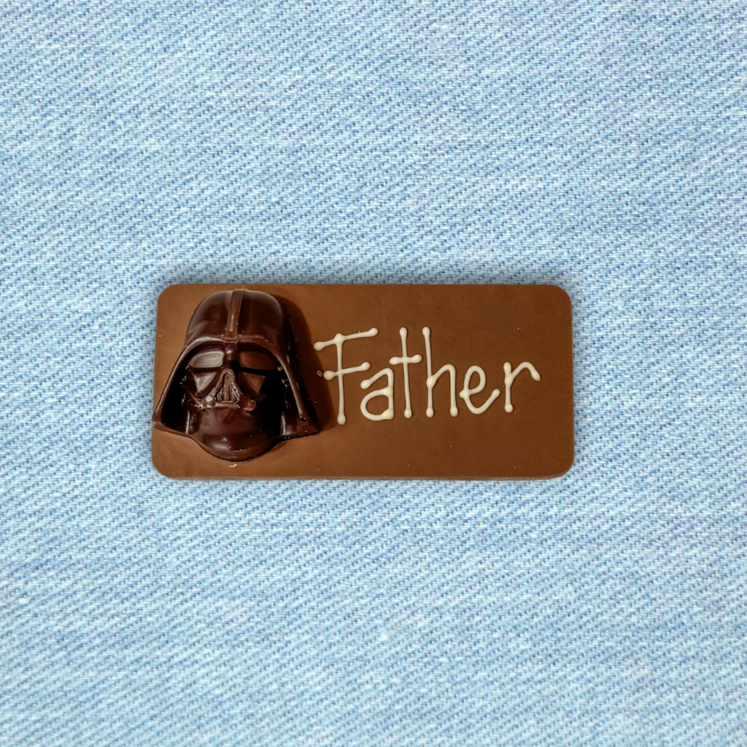 Chocolate bar with Darth Vader design and 'Father' text on a light blue fabric background